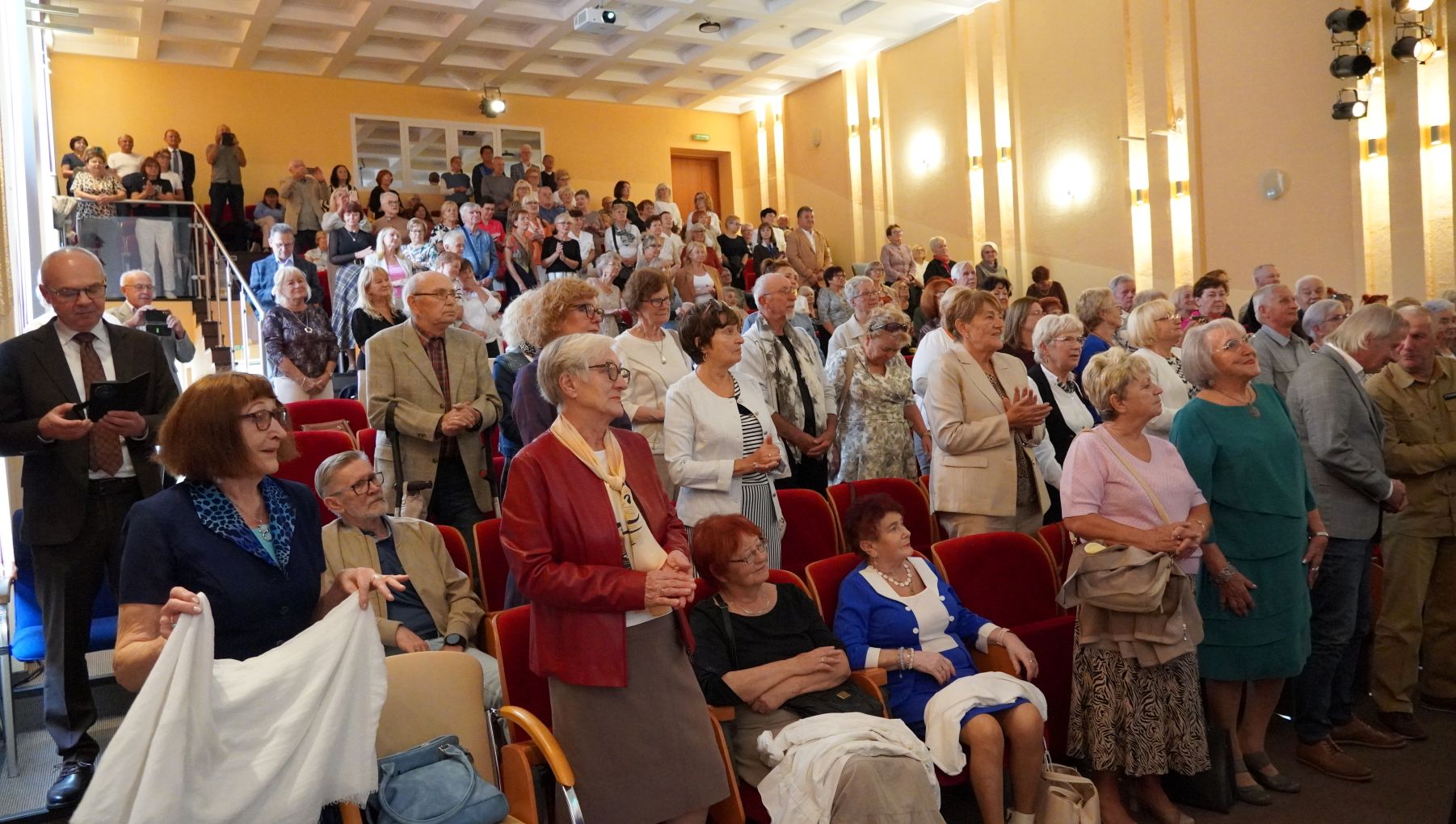 Słuchacze i goście stojący w auli podczas uroczystości inauguracyjnej