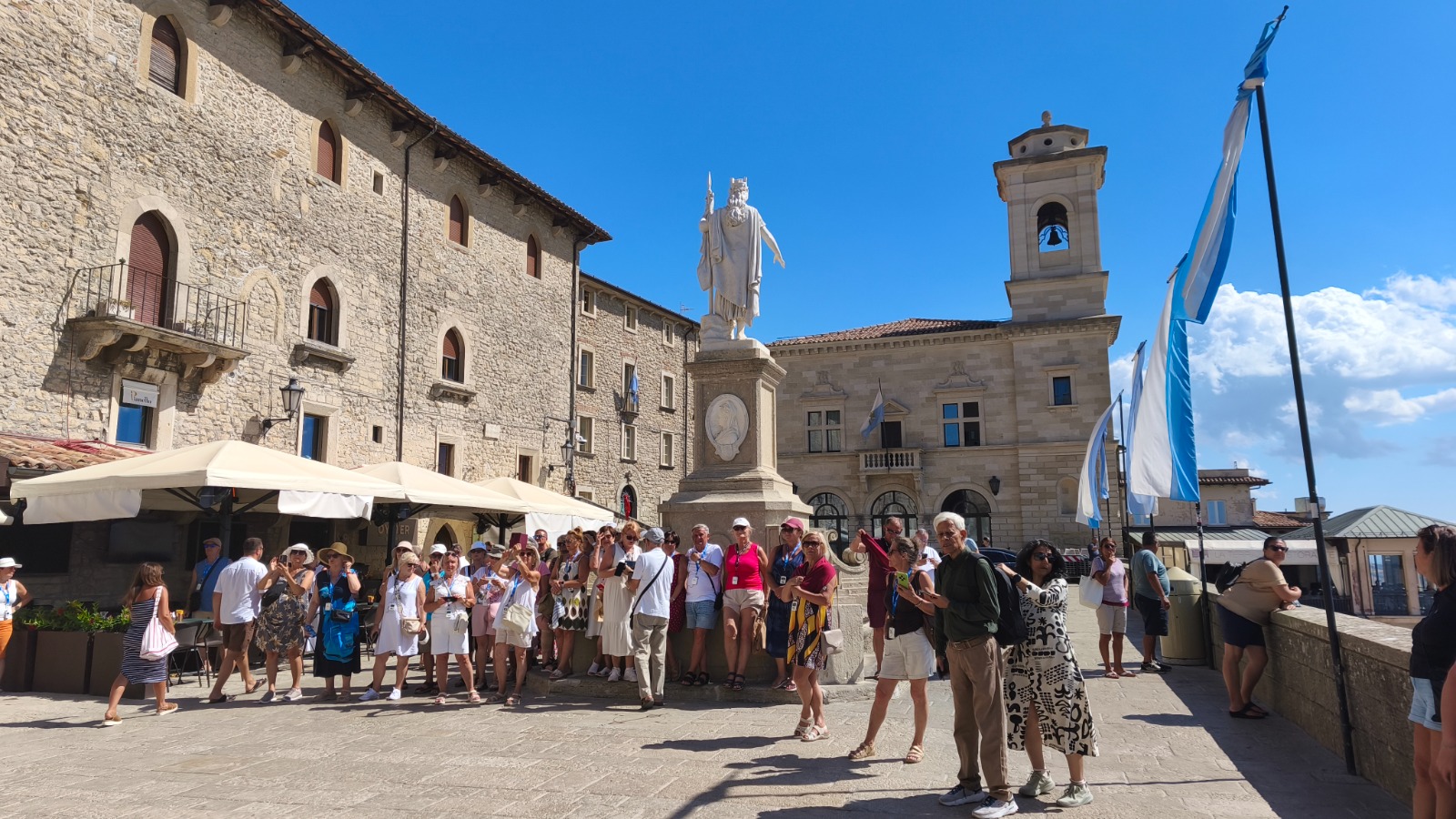 Uczestnicy wyjazdu zwiedzają plac z pomnikiem i flagami San Marino