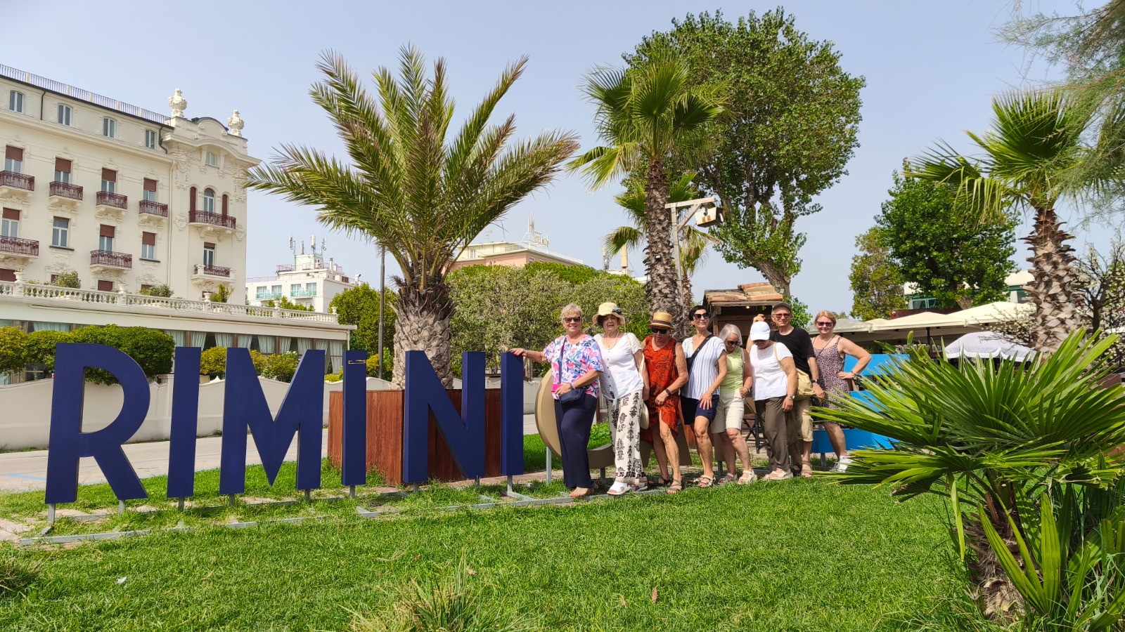 Uczestnicy wyjazdu przy napisie Rimini w otoczeniu palm